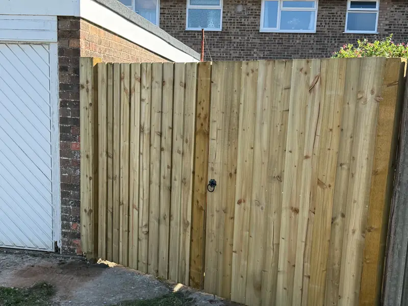 New closeboard fence with a matching gate beside a garage