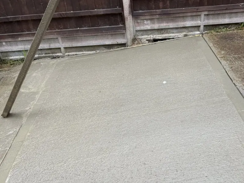 Freshly laid concrete base with timber shuttering along the front edge