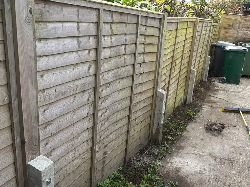 The same fence after the repair, with new concrete spurs bolted to the timber posts